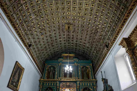  Interior de la iglesia en el que se observa un bello retablo de color verde en el frente y un dorado en el techo.