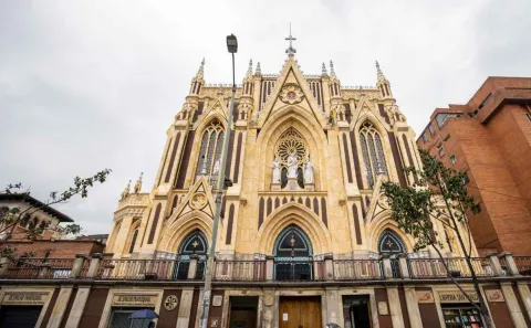 Primer plano de frente de la fachada gótica de la iglesia con algunas edificaciones alrededor. 