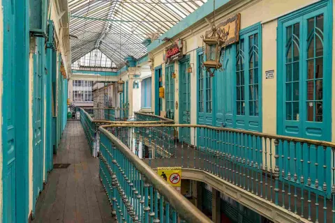 Interior view of the second floor of an old building, featuring turquoise doors and gold handrails.