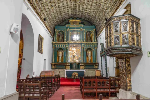 Capilla interior de la iglesia en la que se destacan el altar y el púlpito en madera tallada.
