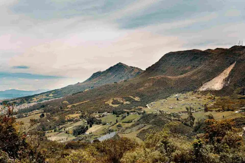 A view of a valley surrounded by mountains, with a small village in the background.