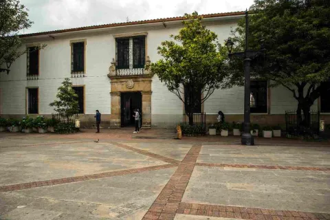 Un patio exterior con un edificio al fondo, rodeado de vegetación y un ambiente tranquilo.