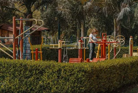 A woman plays on playground equipment, enjoying a sunny and fun day.