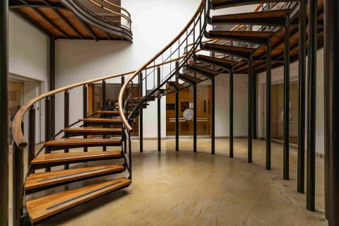 Escalera de caracol en un edificio, combinando madera y metal en su diseño elegante y moderno.