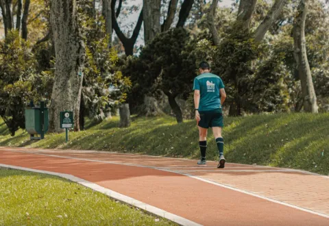 A man walking along a path. Wearing shorts and sneakers, he appears to be exercising.