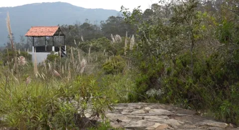  Una pequeña cabaña en la cima de una colina, rodeada de un paisaje natural y cielo despejado.