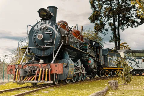 Un tren antiguo en las vías, cubierto de graffiti colorido y desgastado por el tiempo.