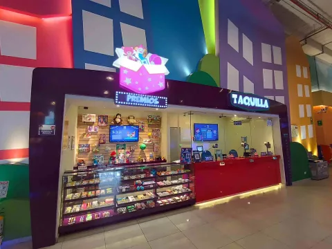  Mostrador de premios y taquilla en un centro de entretenimiento interior, con vitrinas llenas de juguetes y luces coloridas.
