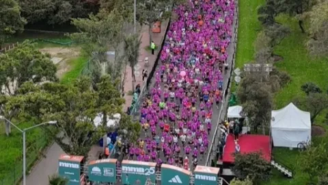 An aerial view of a crowd of runners dressed in pink moving along a track during a race.
