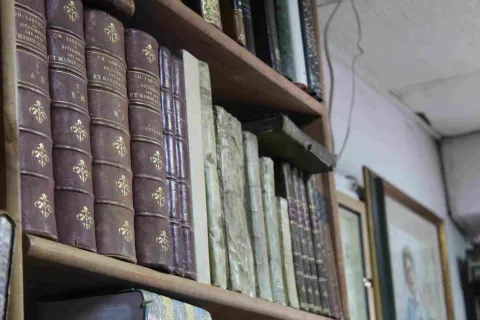 Close-up of antique leather-bound books on a wooden shelf.