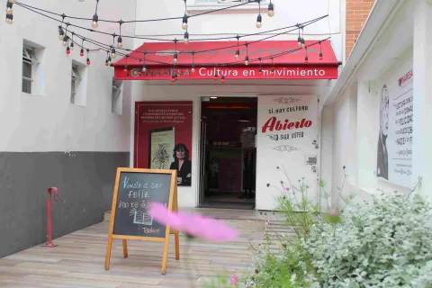 Entrada de la librería Tornamesa con toldo rojo, luces colgantes y un tablero con mensaje en la acera.