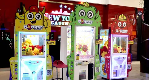 Máquinas de juego tipo garra con peluches en un centro comercial, decoradas con personajes coloridos de Playland.