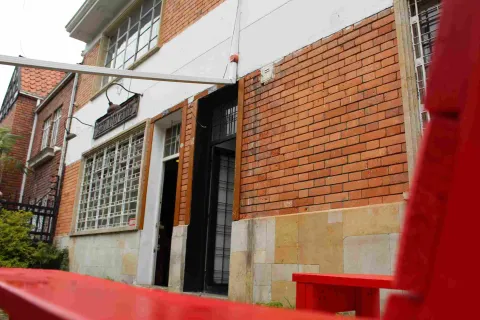 Entrada de la librería San Librario en fachada de ladrillo, con banca roja en primer plano.