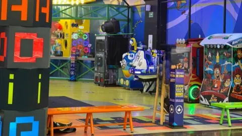  Zona de juegos arcade en interior con máquinas recreativas, luces de colores y áreas de descanso.