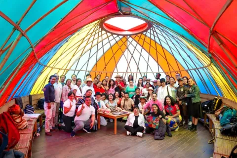  Grupo de personas reunidas dentro de un domo colorido participando en un encuentro comunitario.
