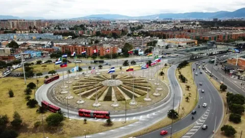 Vista aérea del Monumento a las Banderas en una rotonda, rodeado de vías y tráfico en la ciudad.
