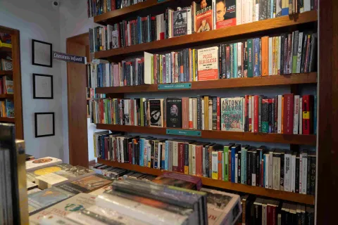  Estantería de madera llena de libros organizados por categorías, con títulos de historia y literatura en una librería.