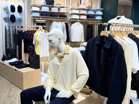 Interior de una tienda de ropa con prendas exhibidas en estanterías y un maniquí vestido con ropa casual elegante.