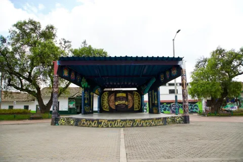 Escenario cubierto en la plaza de Bosa con murales coloridos y la frase “Bosa territorio ancestral”.