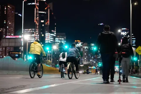 People ride through the illuminated streets of Bogotá during the Ciclovía at night, an event that transforms the city into a space for meeting, sport, and urban enjoyment under the glow of its skyscrapers.