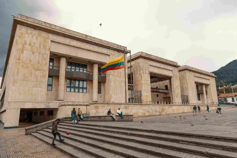 De lado, fachada de estructura con tres edificaciones en piedra. Sobresale al frente izada una bandera de Colombia.