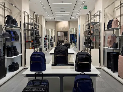 Interior de una tienda de equipaje y accesorios con mochilas, maletas y bolsos exhibidos en estanterías modernas.