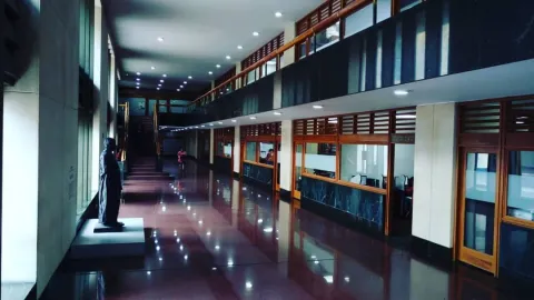 Interior de oficinas alrededor de un pasillo en el que el piso es oscuro y brillante. Hay una estatua en todo el centro del pasillo.