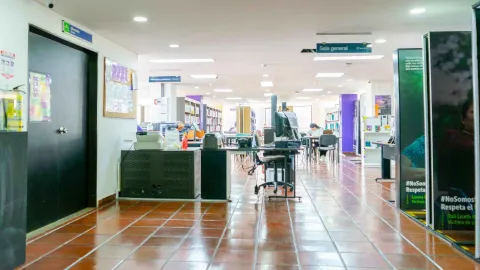 Service and reference area in a library, with service desks, "General Reading Room" signage, and users working in a spacious and organized environment.