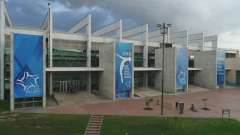 Fachada del Complejo Acuático de Bogotá, una moderna instalación deportiva con amplios accesos, estructuras contemporáneas y espacios diseñados para la práctica de disciplinas acuáticas de alto rendimiento y recreación.