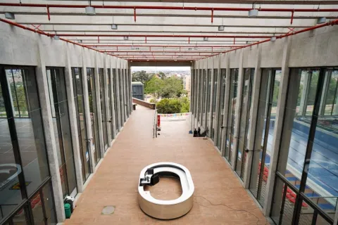  Amplio corredor interior del Centro Felicidad Cometas, con altos ventanales de piso a techo que permiten la entrada de luz natural y ofrecen vistas hacia las zonas verdes circundantes, destacando el diseño moderno y abierto del espacio.