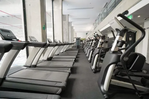  Moderno gimnasio del Centro Felicidad Cometas equipado con caminadoras y máquinas de entrenamiento cardiovascular, en un espacio amplio, iluminado y diseñado para promover la actividad física y el bienestar de los usuarios.