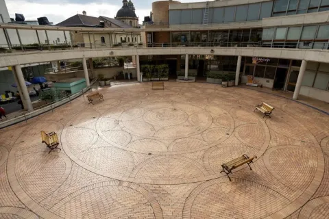 Plazoleta México del Centro Cultural Gabriel García Márquez en Bogotá, un amplio espacio abierto con pisos de ladrillo dispuestos en patrones circulares y bancas distribuidas alrededor. La plaza está rodeada por corredores y edificios de ladrillo diseñados por Rogelio Salmona, con vistas al entorno histórico de La Candelaria.
