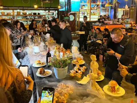 People enjoy a dining experience at a restaurant, taking photos and savoring different dishes and drinks at a decorated table.