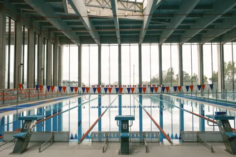 Piscina cubierta semiolímpica del Centro Felicidad Cometas, con carriles demarcados, amplios ventanales que permiten la entrada de luz natural y una infraestructura moderna diseñada para la práctica deportiva y recreativa de la natación.