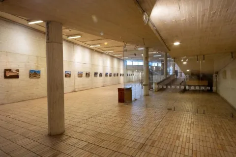Sala de exposiciones Débora Arango del Centro Cultural Gabriel García Márquez, un amplio espacio interior con pisos y muros de ladrillo claro, columnas de concreto y una muestra fotográfica exhibida a lo largo de las paredes. El lugar está diseñado para albergar exposiciones temporales de arte y cultura.