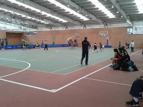 Interior view of a coliseum at the High-Performance Center in Bogotá during a basketball game, with players competing and spectators in the side stands.