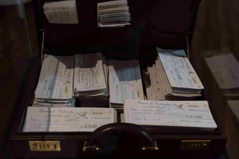 An open briefcase containing numerous old checks from the Bank of Colombia, displayed as historical documents in a museum.