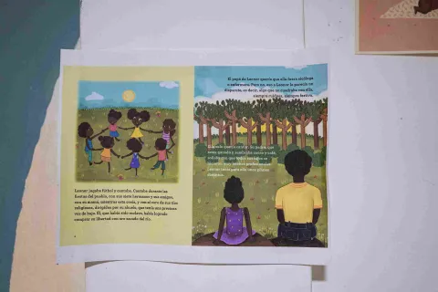 An illustration from an open children's book depicting Afro-Colombian children playing and sharing, accompanied by texts about their history and traditions.