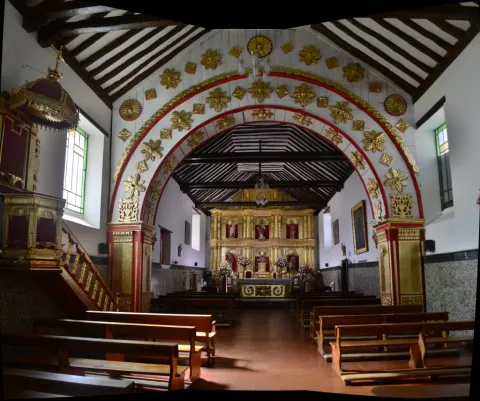  Interior de la Iglesia Doctrinera de Sáchica con arcos decorados, altar dorado de estilo colonial y bancas de madera para los visitantes.