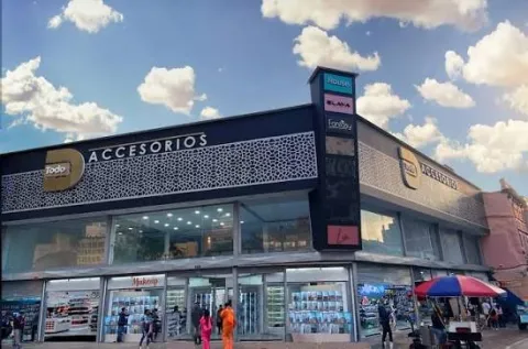 Fachada de un moderno centro comercial especializado en accesorios, con amplios ventanales, locales comerciales y una concurrida zona peatonal. Su diseño contemporáneo y la actividad del entorno reflejan el dinamismo comercial de San Victorino, en el centro de Bogotá.