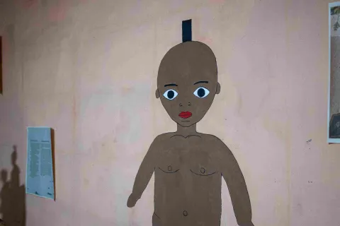 An illustration of an Afro-Colombian figure with large eyes and red lips, displayed on a wall as part of an art and cultural exhibit.