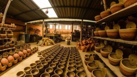 Taller artesanal en Ráquira con estanterías llenas de piezas de cerámica y vasijas de barro elaboradas a mano por artesanos locales.