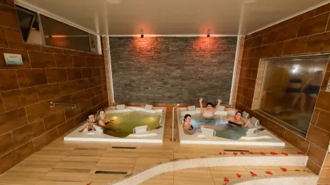  Dos jacuzzis con varias personas disfrutando de un momento de relajación y bienestar en un espacio amplio, cálido y acogedor.