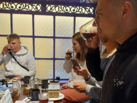 Visitantes participan en una cata de café, degustando diferentes preparaciones mientras exploran sus aromas y sabores en un ambiente acogedor, rodeados de utensilios y métodos de preparación de café de especialidad.
