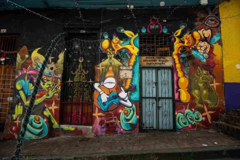 Fachada colorida del Callejón del Embudo, decorada con llamativos murales de arte urbano, figuras fantásticas y referencias a la cultura bogotana.