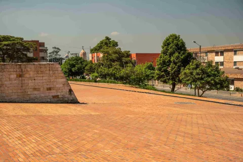 Plazoleta de ladrillo del Archivo de Bogotá, rodeada de árboles y con edificaciones del sector al fondo.