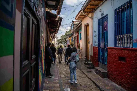 Callejón del Embudo en La Candelaria, con visitantes recorriendo su estrecha vía empedrada entre casas tradicionales de colores y arte urbano.