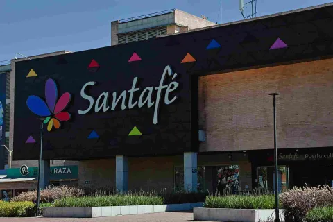 El colorido logo de Centro Comercial Santafé destaca sobre su moderna fachada, rodeada de amplias zonas verdes y espacios abiertos. Una imagen que refleja el carácter contemporáneo y acogedor de este importante punto de encuentro del norte de Bogotá.