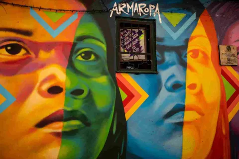 Mural de arte urbano en el Callejón del Embudo, con coloridos rostros y figuras que llenan de identidad y creatividad las paredes de La Candelaria.