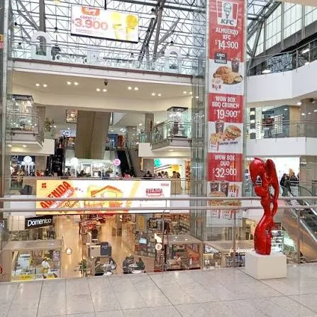 Una vista interior del Centro Comercial Avenida Chile, donde tiendas, espacios abiertos y elementos artísticos crean un ambiente moderno y dinámico.